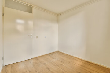 an empty room with wood floors and white walls, the door is open to reveal a closet in the corner
