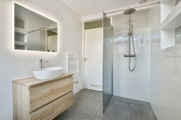 a bathroom with a sink, mirror and shower head mounted on the wall next to it is a wooden vanity