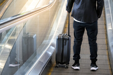Baggage claim and airport check in concepts. Casual style male traveler passenger with black wheels...