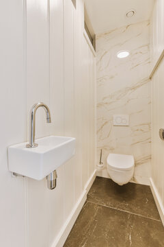 a white bathroom with marble flooring and wall to wall tile in the shower stall, which is also used as a toilet
