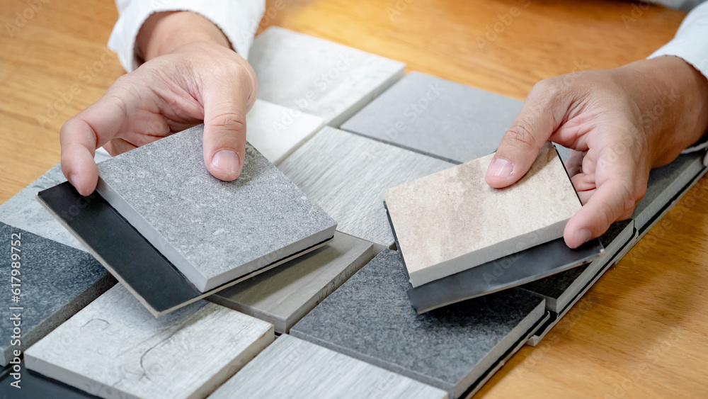 Wall mural architect hand choosing sample of stone material or tile texture collection on the table in studio. 