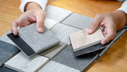 Architect hand choosing sample of stone material or tile texture collection on the table in studio....