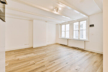 an empty room with wood flooring and white paint on the walls there is a large window in the corner