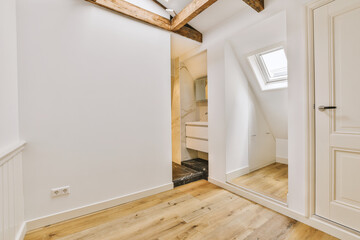 a room with wood flooring and white walls, an open door to the bathroom is visible on the right side