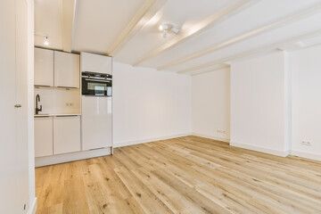 an empty living room with wood floors and white cupboards on either side of the room, there is a stove in the corner