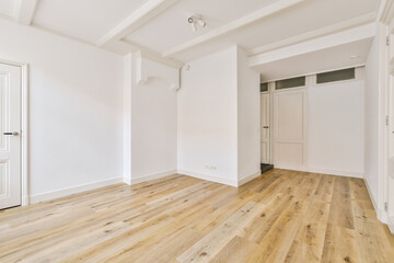 an empty room with white walls and wood flooring on the right, there is a door to the left