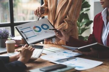 Businesswoman teamwork, discussing, brainstorming, pointing to earnings, income, taxes data in conference room. Focus on business growth and point out financial accounting charts.