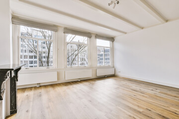 an empty living room with wood flooring and white walls, windows overlooking out onto the street in new york