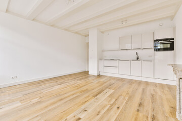 an empty living room with wood floors and white cupboards on the wall, there is a microwave in the...