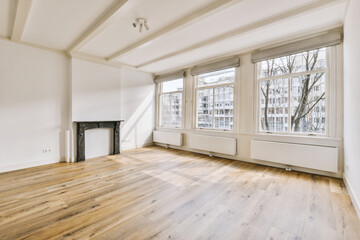 an empty living room with wood flooring and large windows looking out onto the street in front of...