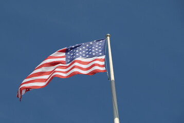 The American flag soars into deep blue sky