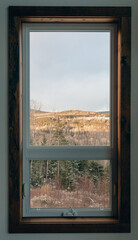 vue au travers d'une fenêtre avec un cadre en bois sur une forêt au bas à partir de l'intérieur d'une maison lors d'une journée ensoleillée