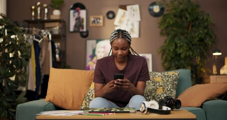African skilled multitasker, using cellphone to manage her busy schedule, set reminders, and stay organized with productivity apps, feeling efficient and in control of her day.