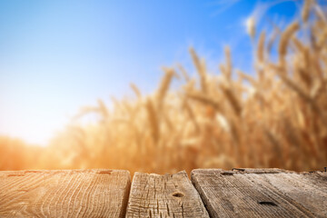 Empty wooden table in golden wheat field © Pixel-Shot