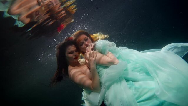 two sexy ladies swimming underwater inside magical sea or ocean, fashion models looking seductively