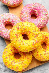 Board with sweet donuts on grey grunge background