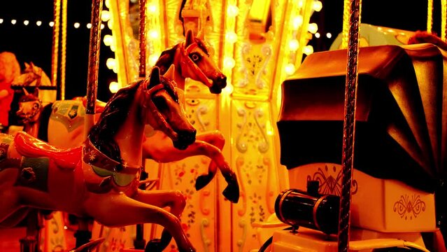 children's retro carousel fun rotates in a dark park, decorated with light bulbs, decorations, spinning merrily, fairground attraction in park with horses for children, concept of holiday, Christmas