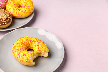 Plates with sweet donuts on light background