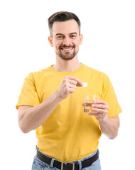 Young man with soluble tablet and glass of water on white background