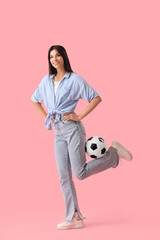 Young woman with soccer ball on pink background