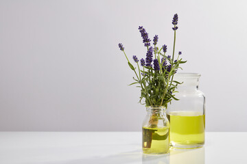 Minimal scene of two glass transparent vases with yellow liquid inside. Lavender (Lavandula) has antioxidant activity that good for health. Vacant space to display cosmetic product