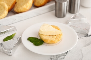 Plate with crouton and triangles of tasty processed cheese on white marble background