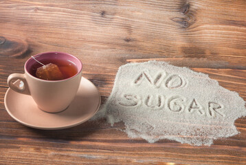 On a brown background is a pink cup with tea, a pile of sugar with the inscription - no sugar. The...