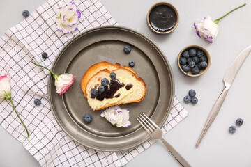 Plate with delicious jam toasts, blueberries and flowers on grey background