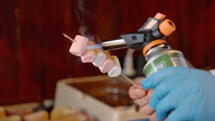 Close up view of men's gloved hands making a caramel crust on a marshmallow with a burner