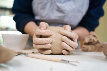 Obraz na płótnie Canvas woman forming clay pot shape by hands, closeup in artistic studio