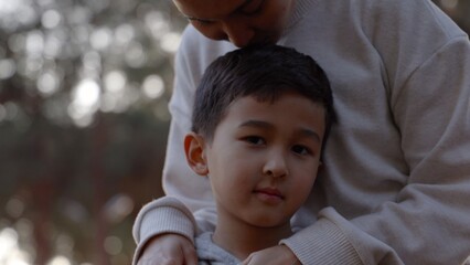 Portrait of little boy looking at camera when mother holds him