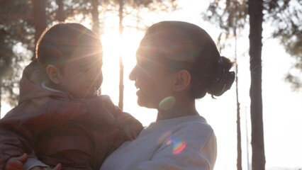 A loving mother holding her baby and and kissing him tenderly in nature 