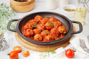 Frying pan of tasty meat balls with tomato sauce and dill on white background