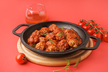 Frying pan of tasty meat balls with tomato sauce and dill on red background