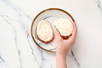 Woman eating tasty sandwiches with cream cheese on white marble background