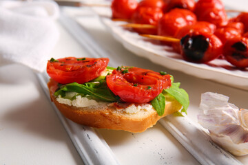Plate of skewers with tasty grilled tomatoes and sandwich on white background