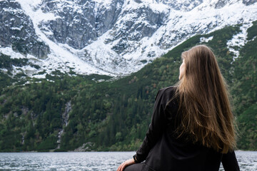 Naklejka premium Young woman enjoying nature in Morskie Oko Snowy Mountain Hut in Polish Tatry mountains Zakopane Poland. Naturecore aesthetic beautiful green hills. Mental and physical wellbeing Travel outdoors