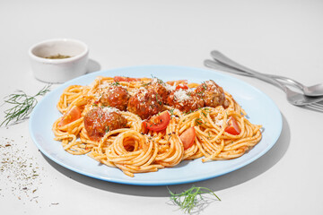 Plate of boiled pasta with tomato sauce and meat balls on white table