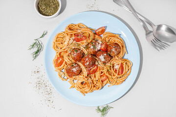 Plate of boiled pasta with tomato sauce and meat balls on white table
