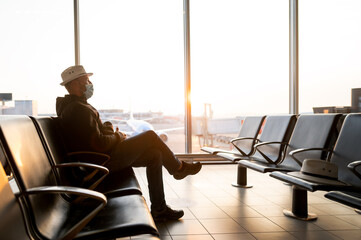 Mature businessman at the airport in the waiting room. Portrait of latin man sitting with mask