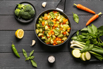 Frying pan with different vegetables on dark wooden background
