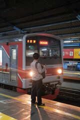 a young man waiting on a train on the platform. a worker in jakarta waiting for the train to go home. person in the subway.