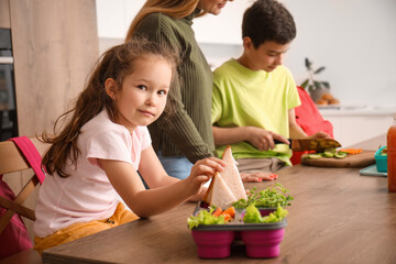 Little girl with school lunch in kitchen