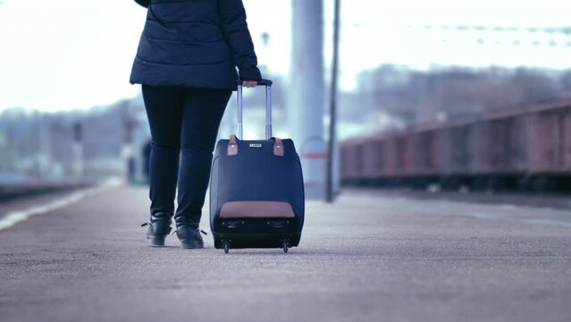 Solitary Departure: Woman's Journey through a Cool, Sunless Railway Station with a Suitcase