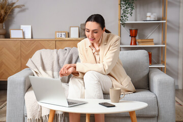 Young businesswoman with laptop video chatting at home