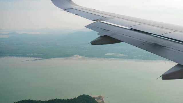 First-person view from the porthole to the island of Phuket. Passenger flight arrival. Airplane decline to Thailand