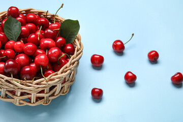 Wicker bowl with sweet cherries on blue background
