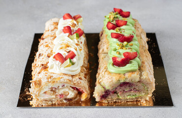 Two meringue rolls with strawberries, lime and pistachios on light gray background, Closeup