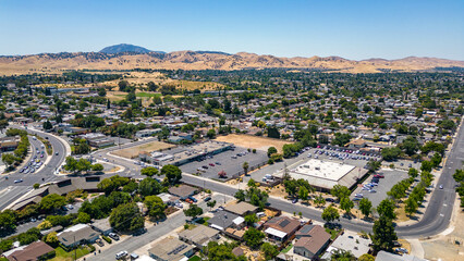 Drone photo over a neighborhood in Antioch, California with houses, commercial buildings and a blue...