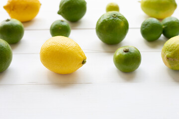 Ripe lemons and limes on white wooden.